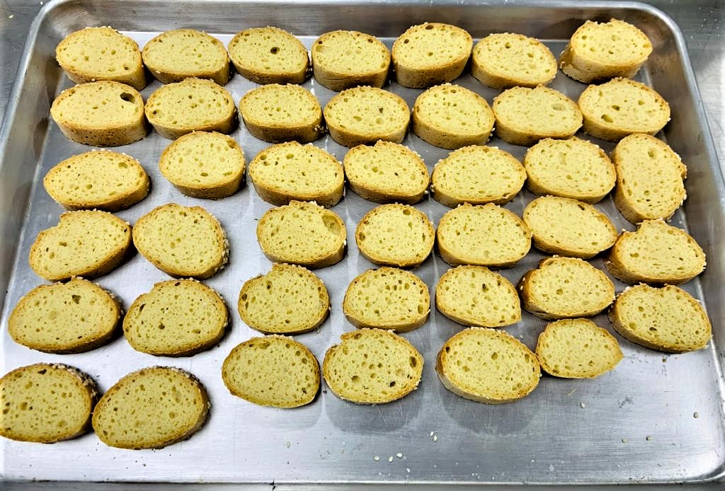 Se observa sobre una bandeja, rebanadas de pan tipo baguette y los alveolos (huecos) provocados por fermentación.